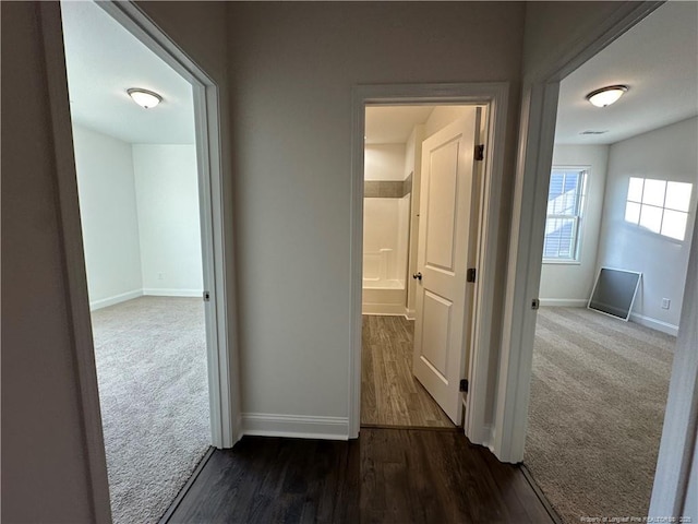 corridor featuring dark colored carpet