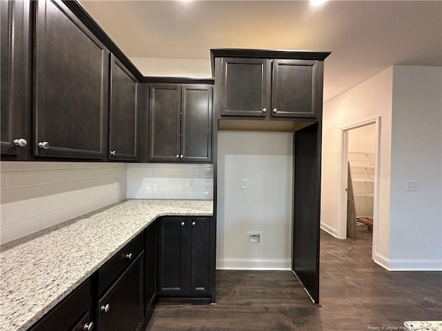 kitchen featuring light stone counters, dark brown cabinets, dark hardwood / wood-style floors, and decorative backsplash