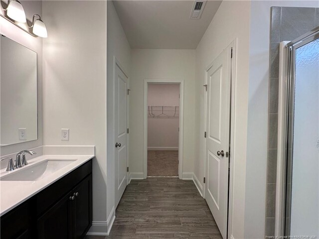 bathroom featuring hardwood / wood-style flooring, vanity, and a shower with shower door