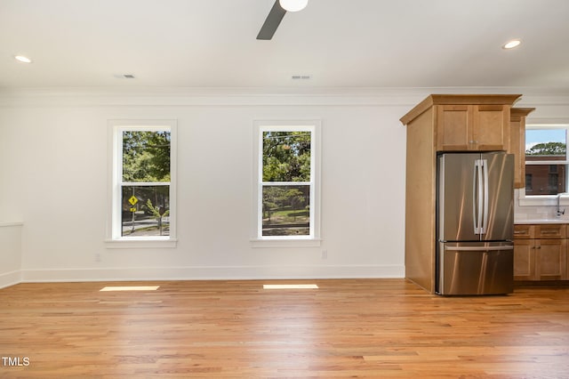 kitchen featuring ornamental molding, light wood-type flooring, plenty of natural light, and stainless steel refrigerator