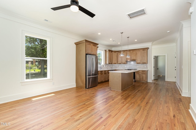 kitchen with a center island, decorative light fixtures, stainless steel fridge, and plenty of natural light