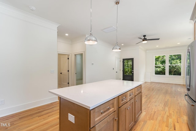 kitchen with hanging light fixtures, ceiling fan, a kitchen island, light hardwood / wood-style flooring, and stainless steel fridge