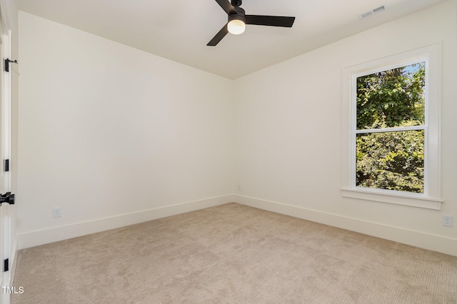 empty room featuring ceiling fan, a wealth of natural light, and light colored carpet