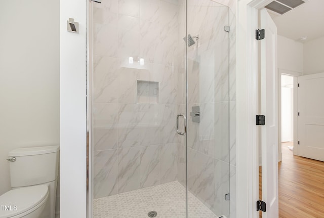 bathroom with toilet, an enclosed shower, and wood-type flooring