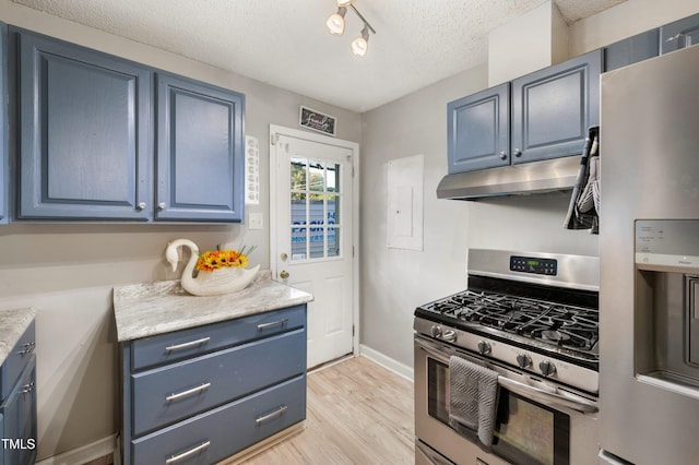 kitchen with stainless steel appliances, rail lighting, blue cabinets, a textured ceiling, and light hardwood / wood-style floors