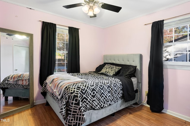 bedroom featuring multiple windows, wood-type flooring, and ceiling fan