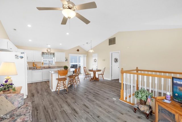 kitchen featuring light hardwood / wood-style flooring, white cabinets, vaulted ceiling, and sink