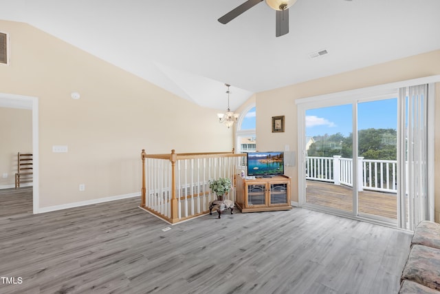 unfurnished living room with hardwood / wood-style floors, ceiling fan with notable chandelier, and vaulted ceiling