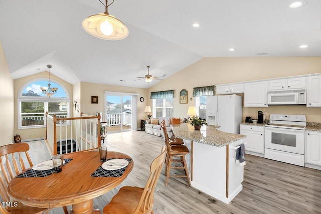 kitchen with pendant lighting, white appliances, a wealth of natural light, and lofted ceiling