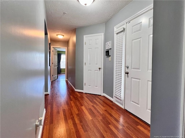 hallway with dark wood-type flooring and a textured ceiling