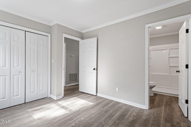 unfurnished bedroom featuring connected bathroom, light hardwood / wood-style floors, a closet, and ornamental molding