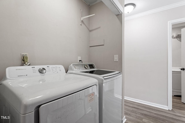 washroom featuring washing machine and clothes dryer, crown molding, and hardwood / wood-style floors