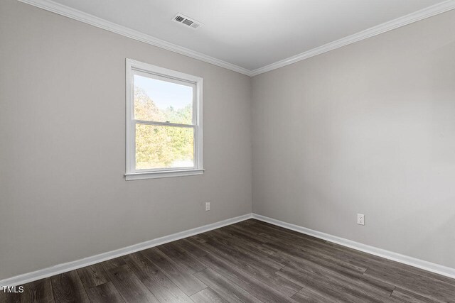 spare room featuring dark hardwood / wood-style floors and crown molding