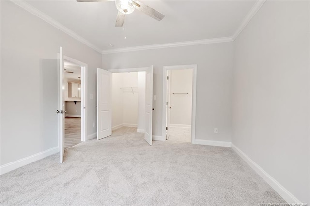 unfurnished bedroom with a walk in closet, light colored carpet, ornamental molding, a closet, and ceiling fan