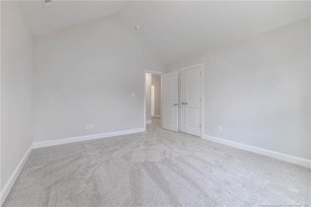 carpeted empty room with high vaulted ceiling