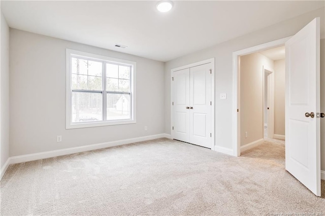 unfurnished bedroom with light carpet and a closet