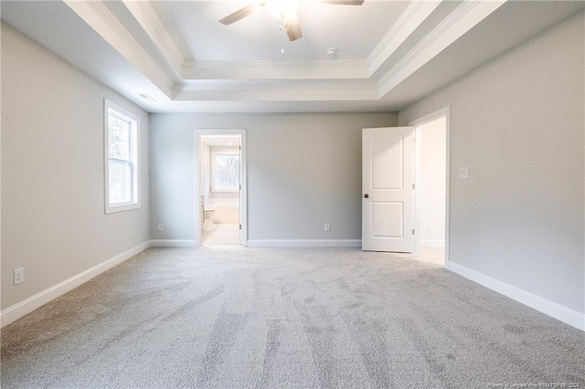 carpeted empty room featuring ceiling fan, ornamental molding, and a tray ceiling