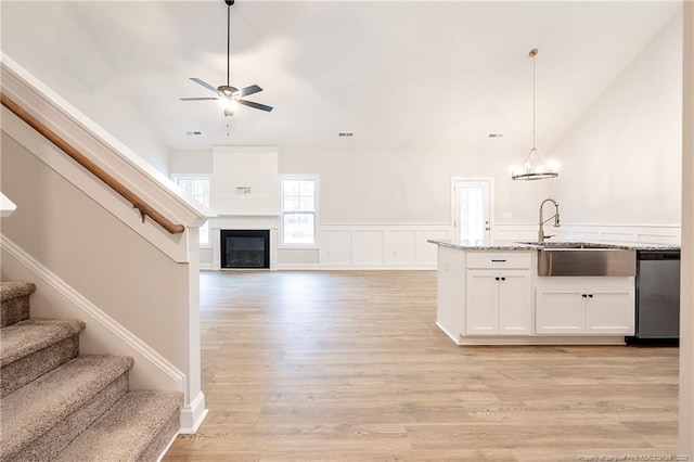 kitchen featuring sink, light stone counters, dishwasher, pendant lighting, and white cabinets