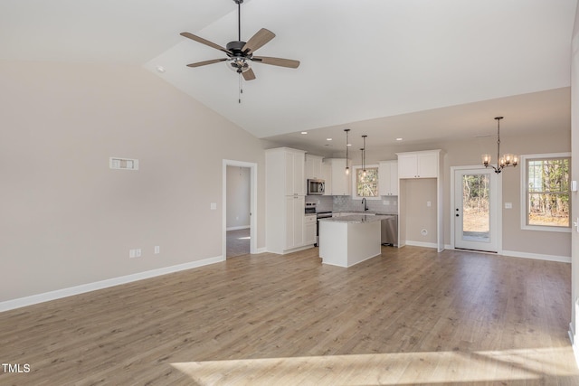 unfurnished living room featuring ceiling fan with notable chandelier, high vaulted ceiling, sink, and light hardwood / wood-style floors