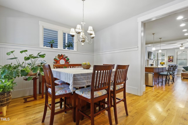 dining space featuring light hardwood / wood-style flooring and ceiling fan with notable chandelier