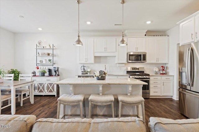 kitchen with a kitchen island, white cabinetry, hanging light fixtures, and appliances with stainless steel finishes