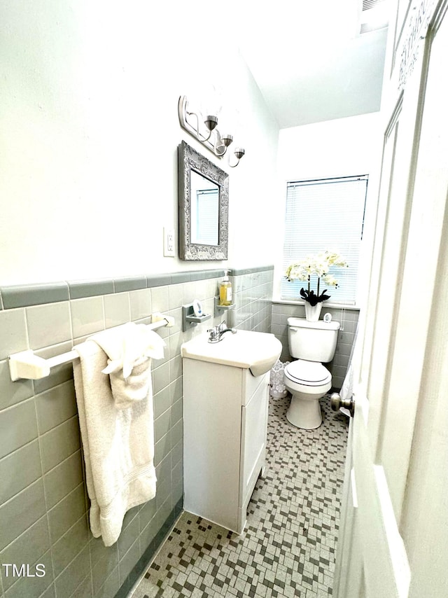 bathroom featuring vanity, tile walls, and toilet