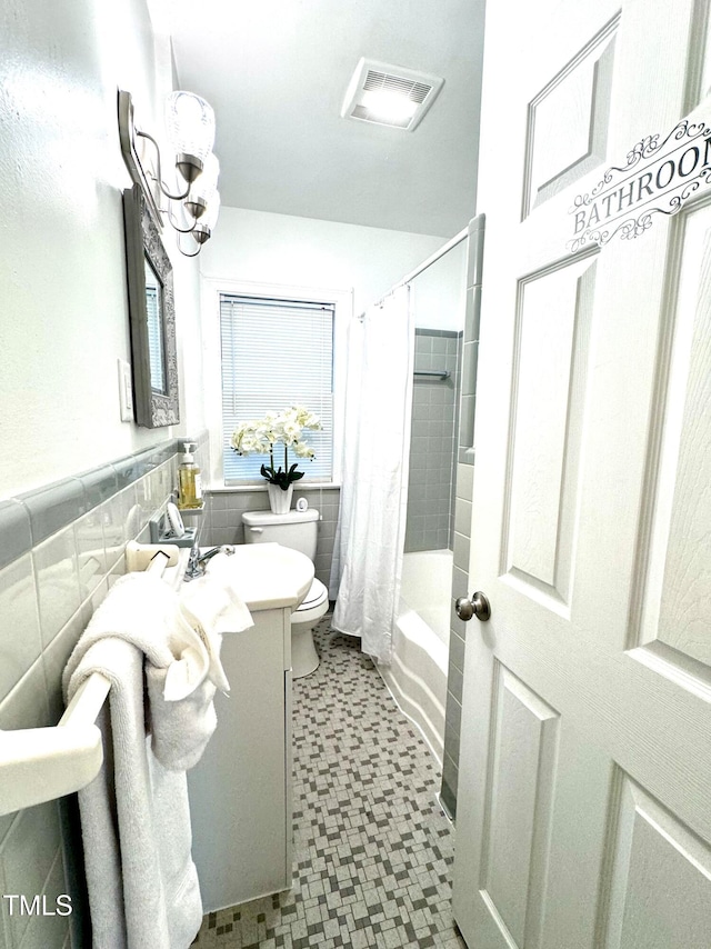 full bathroom with tile walls, shower / tub combo, vanity, and toilet