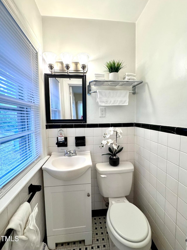 bathroom with vanity, tile walls, and toilet