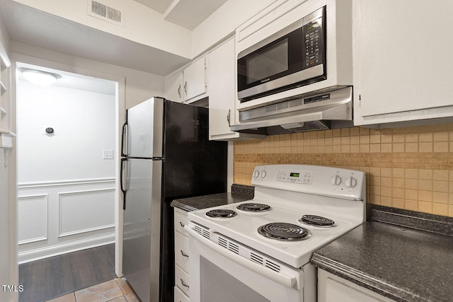 kitchen with white cabinets, exhaust hood, backsplash, light hardwood / wood-style flooring, and stainless steel appliances