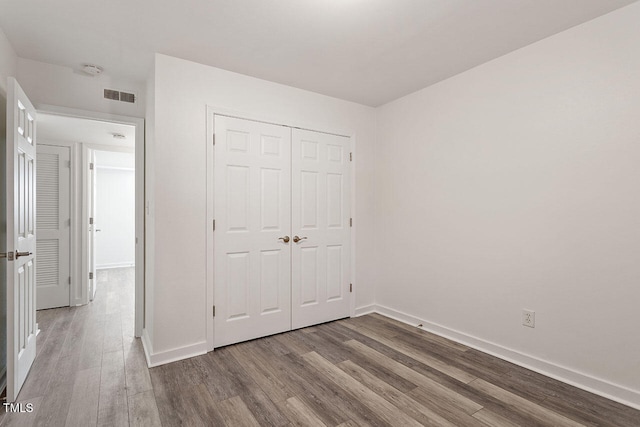 unfurnished bedroom featuring wood-type flooring and a closet