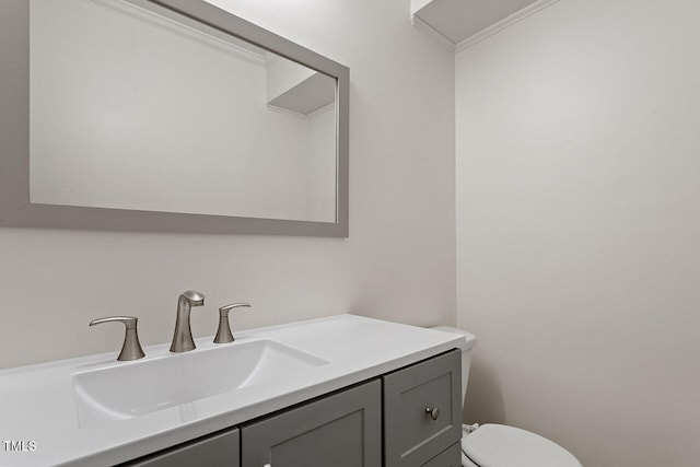 bathroom featuring vanity, toilet, and crown molding