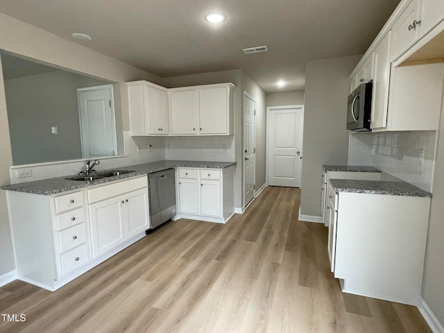 kitchen with light hardwood / wood-style floors, appliances with stainless steel finishes, sink, and white cabinets