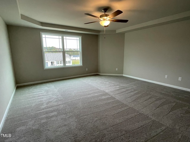 carpeted spare room featuring a raised ceiling and ceiling fan