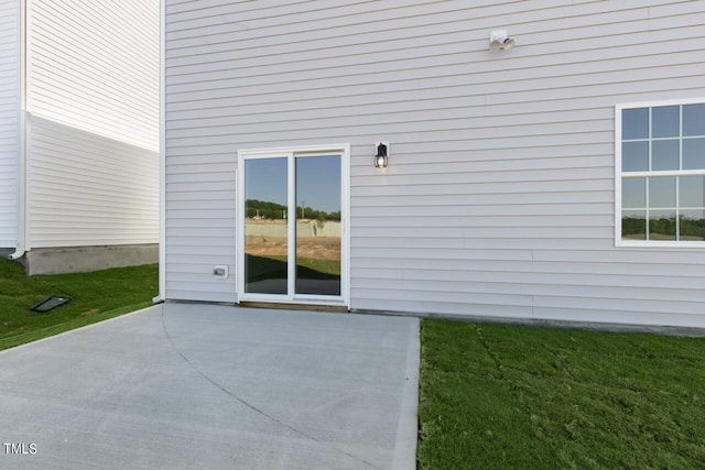 doorway to property with a patio area and a lawn