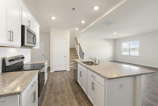 kitchen featuring white cabinets, a kitchen island with sink, stainless steel appliances, and dark wood-type flooring