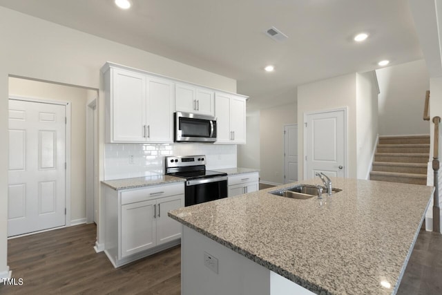 kitchen with stainless steel appliances, a kitchen island with sink, sink, and white cabinets