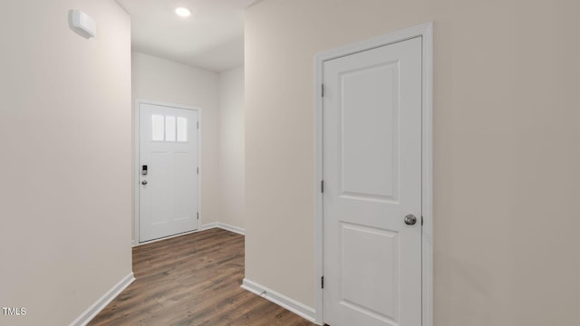 corridor featuring baseboards and dark wood-style floors