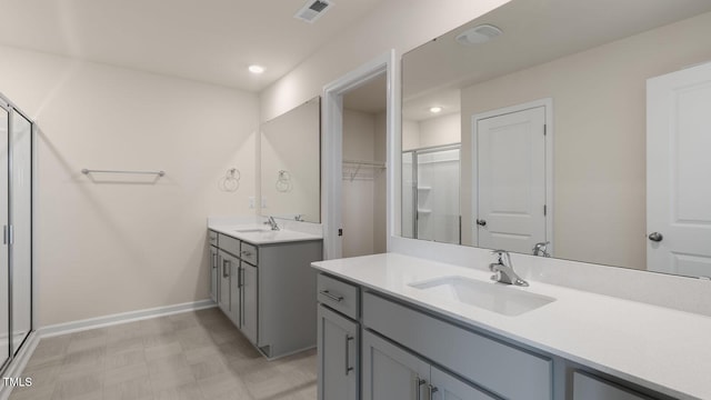 bathroom with a stall shower, baseboards, visible vents, and a sink