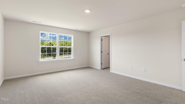 empty room featuring light carpet, visible vents, and baseboards