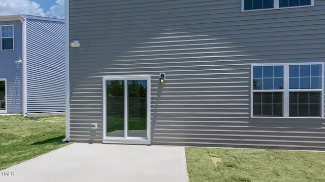 property entrance with a lawn and a patio