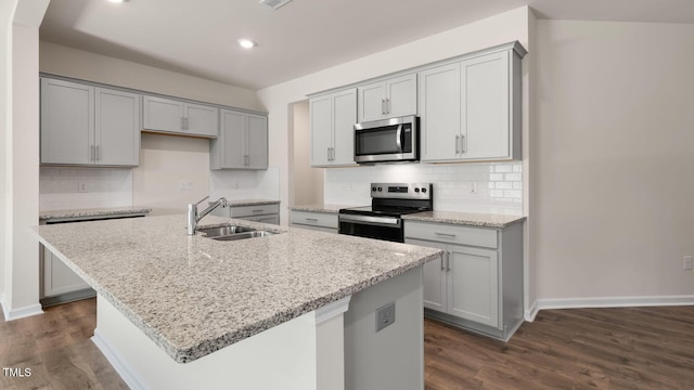 kitchen with dark wood-style floors, an island with sink, gray cabinets, a sink, and stainless steel appliances