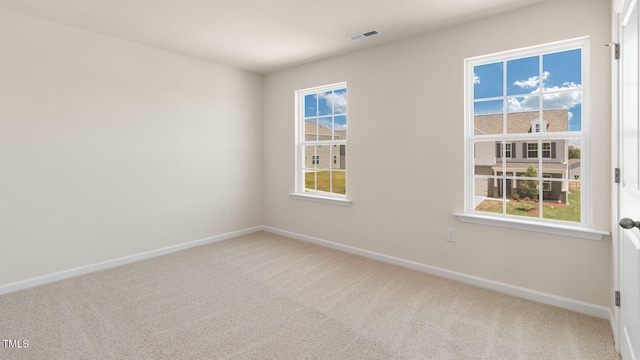 unfurnished room with carpet, visible vents, and baseboards