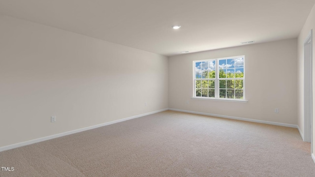 empty room featuring baseboards and light carpet