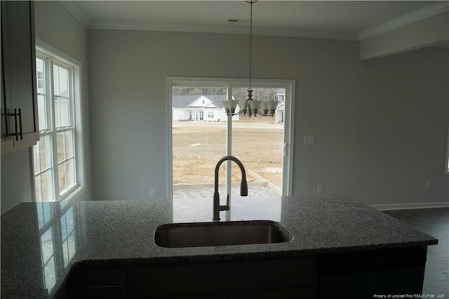 kitchen with stone countertops, crown molding, visible vents, and a sink