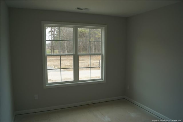 spare room featuring a wealth of natural light, visible vents, and baseboards