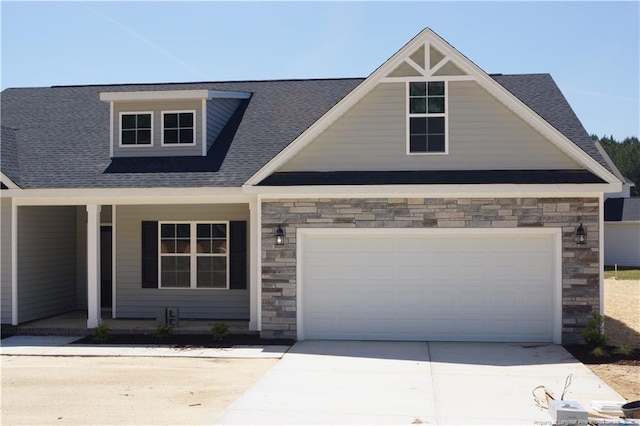 craftsman house featuring a porch, roof with shingles, driveway, and stone siding