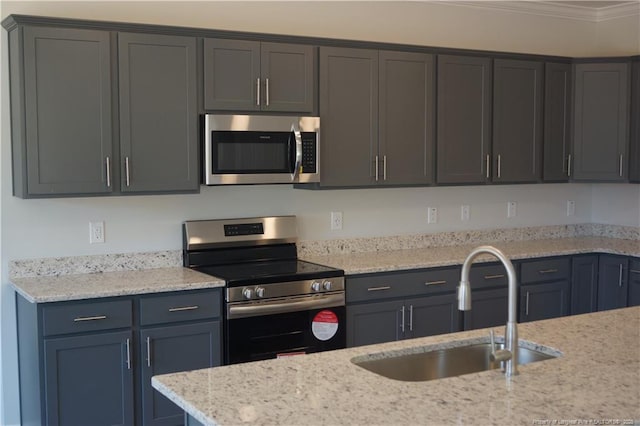 kitchen with crown molding, a sink, appliances with stainless steel finishes, and light stone countertops