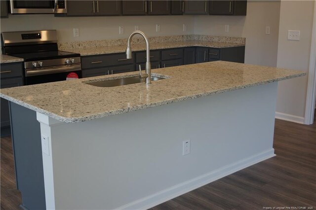 kitchen featuring baseboards, dark wood-style floors, light stone counters, a sink, and stainless steel range with electric cooktop