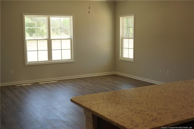 empty room with baseboards and dark wood-type flooring