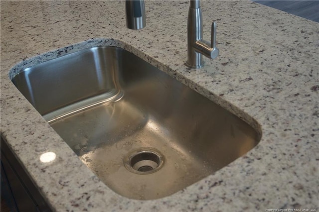 details with a sink and light stone countertops